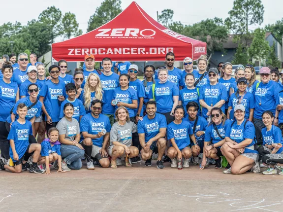 A large group of people wearing Run/Walk shirts in front of a ZERO tent