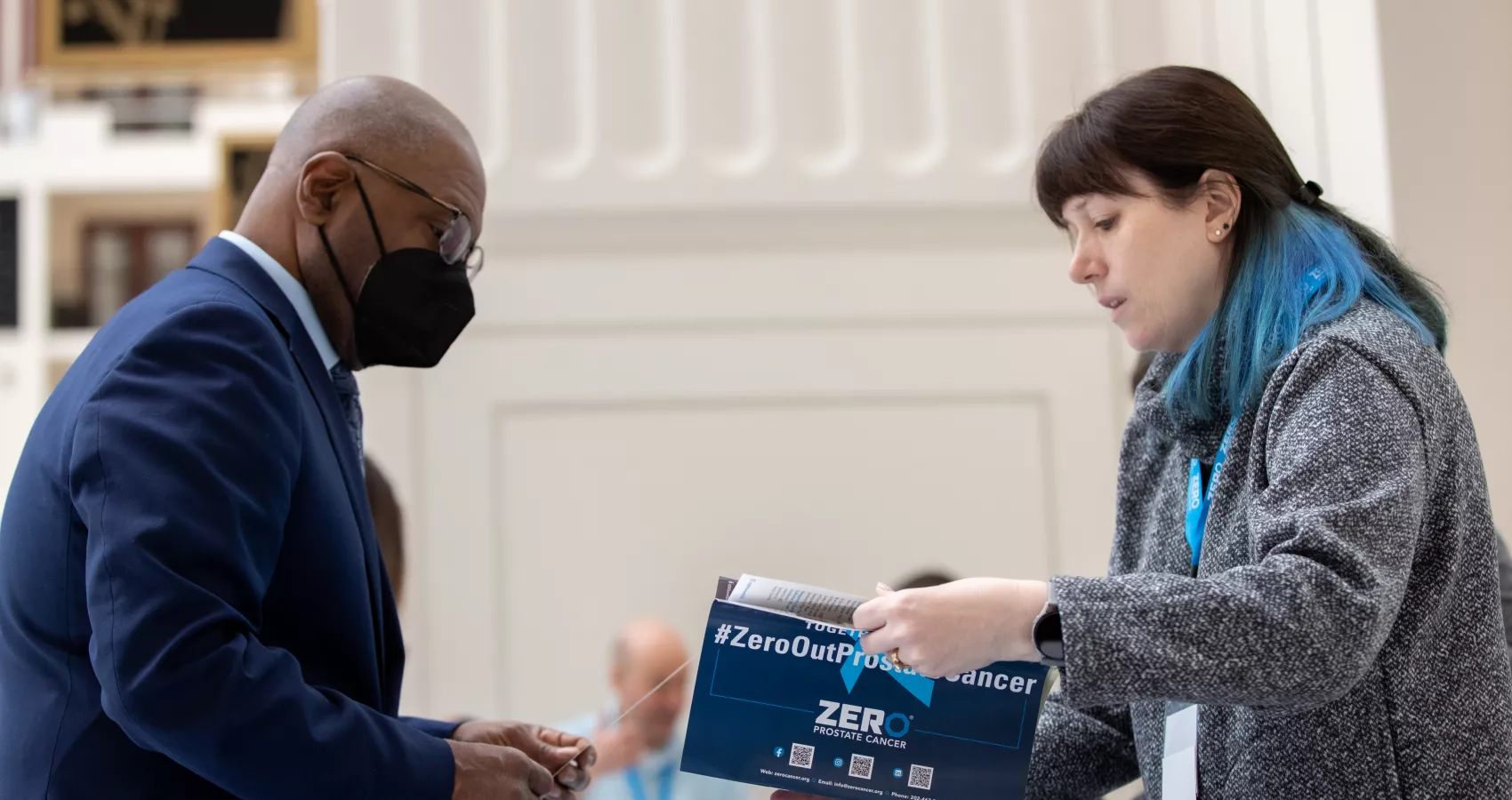 Woman with blue hair highlights showing a brochure to an African American man in suit