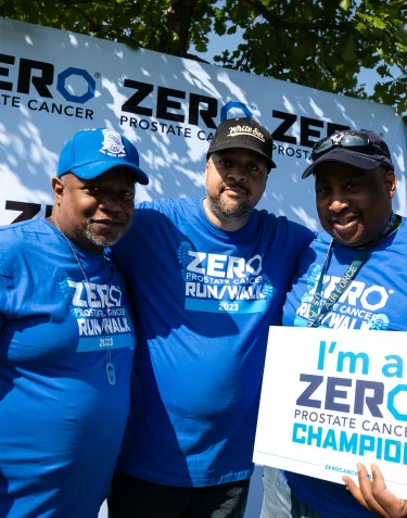 Three African American men wearing blue t-shirts and carrying a We're Champions sign