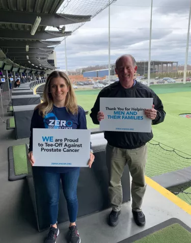 Couple holding We Are Proud to Tee Off against Prostate Cancer sign