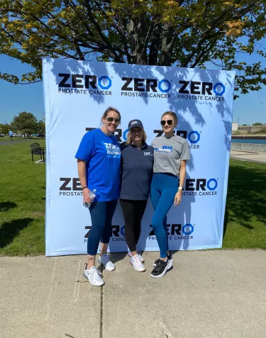 Three people in front of a ZERO banner