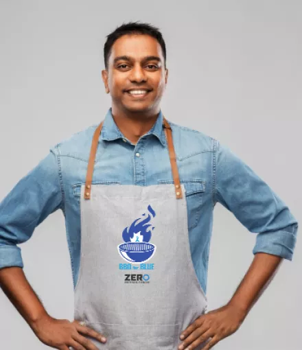 Man wearing an apron that has the BBQ for Blue logo on it