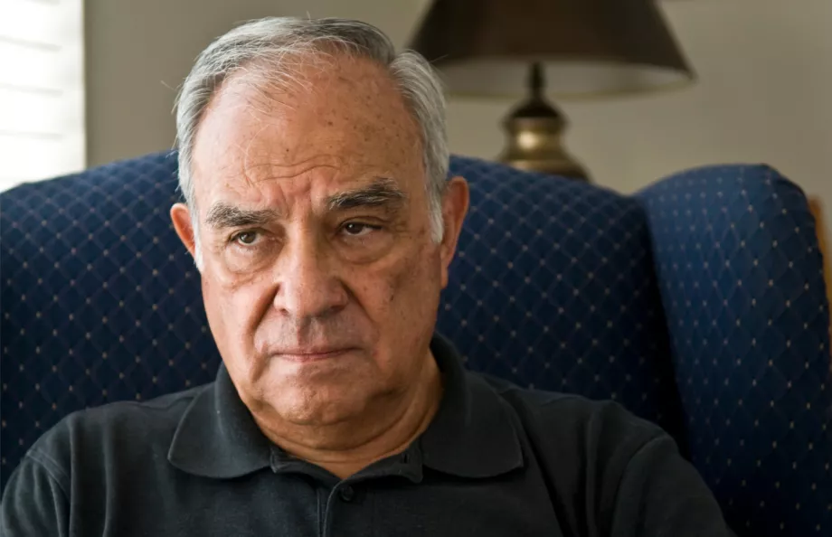 Hispanic man sitting in a living room looking distressed