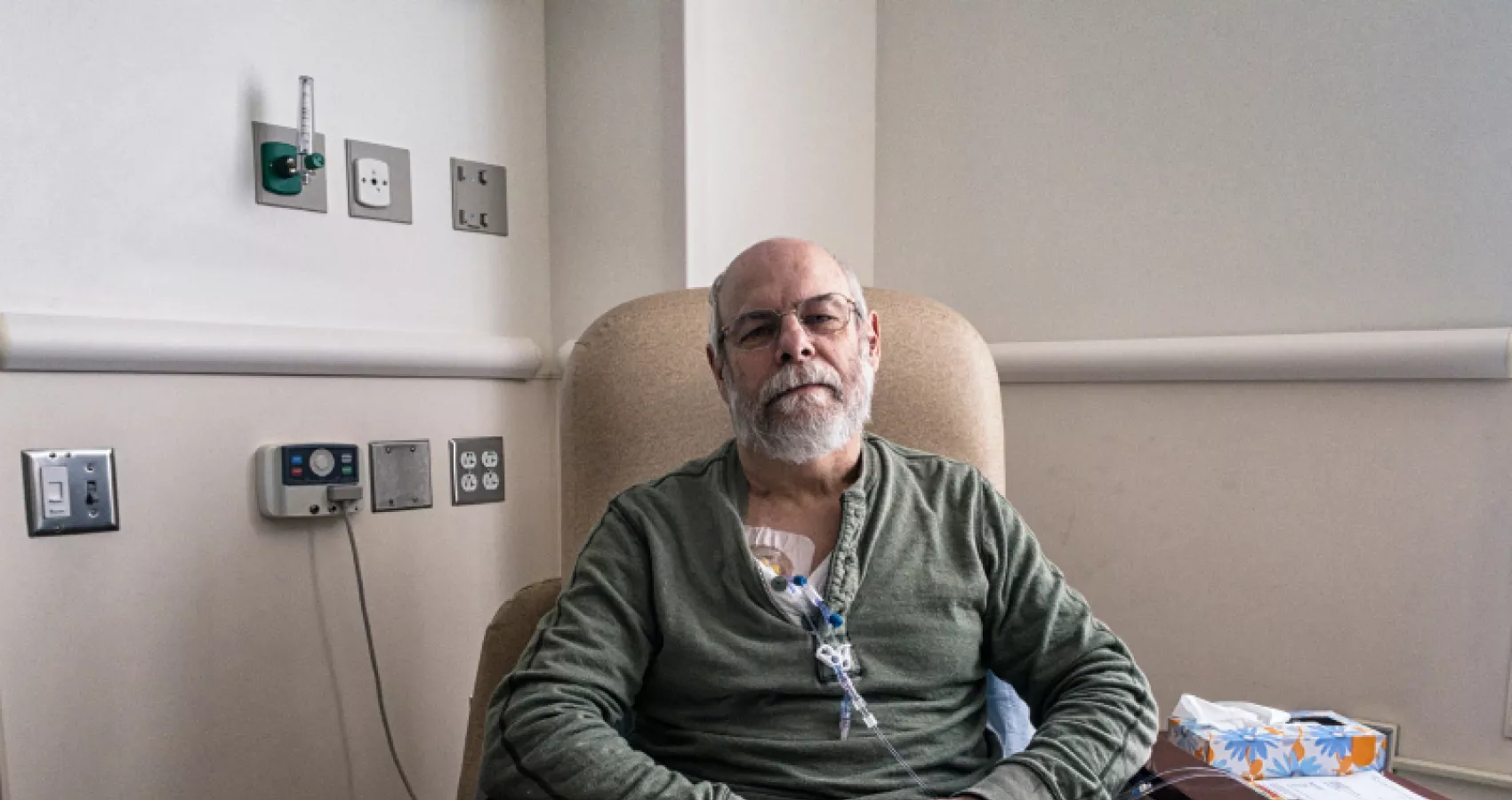 A man sitting in a chair in the hospital receiving chemotherapy treatment
