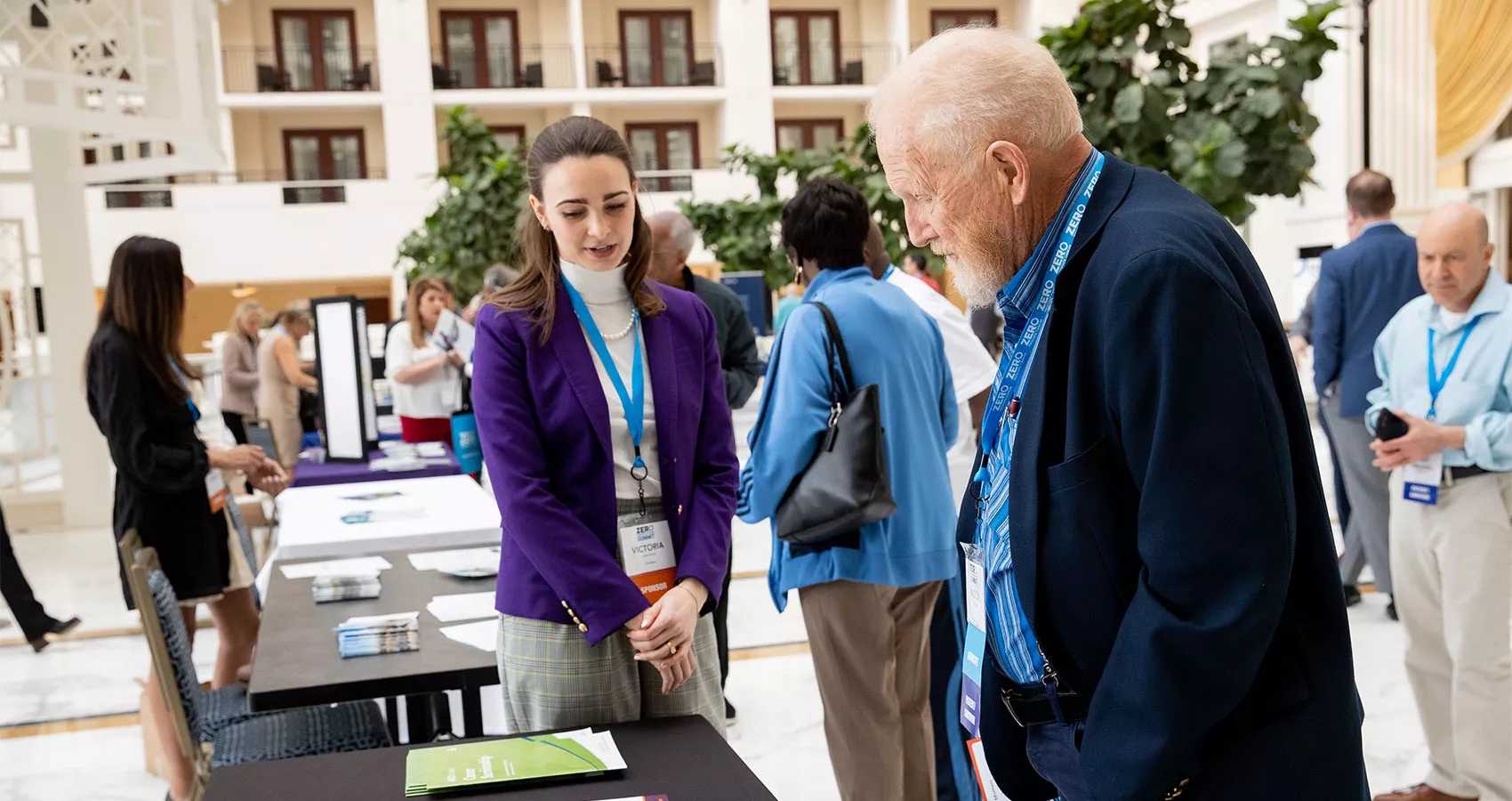 Young woman presenting educational materials to an elderly man at an event stand