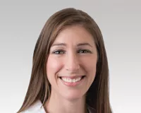 Woman with long brown hair in a white coat, Dr. Alicia Morgans