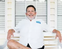 Middle-aged man wearing a white shirt with ZERO Champions logo