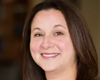 Woman with long dark hair smiling at the camera