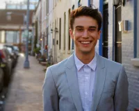 Young man in a light blue suit smiling at the camera