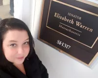 Woman posing next to a senator's plaque
