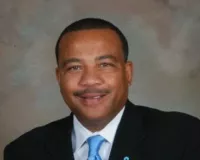 African American man in a dark suit and blue tie