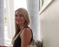 Young blond woman standing next to a wall