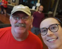 Caucasian man with a baseball hat and glasses taking a selfie with a girl with glasses