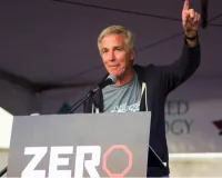 A man giving a speech at a rally with his left hand up