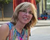 A middle aged blonde woman wearing a colorful shirt