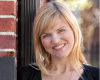Headshot of a blonde woman standing next to a brick wall