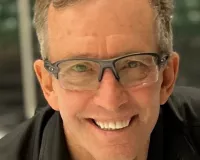 Middle-aged man with blond hair and glasses smiling at the camera