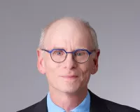 An older white man wearing a suit and tie with glasses