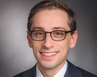 Young man with rectangle glasses posing for a headshot