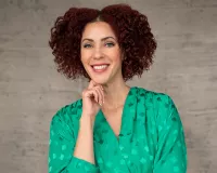 A Black woman in a green top smiling at the camera