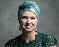 A woman with short blue hair and a green dress