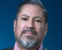 An older hispanic man with slicked grey hair and a goatee
