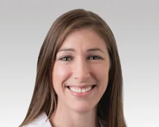 Woman with long brown hair in a white coat, Dr. Alicia Morgans