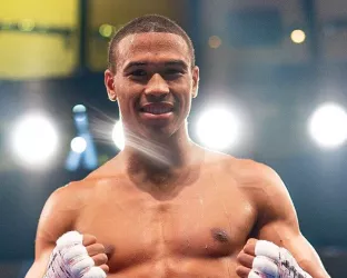 A young, black, shirtless man wearing a boxing uniform