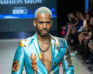 Actor Eric West wearing a light blue floral suit on the runway