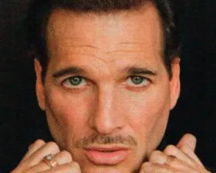 Celebrity Stylist, Phillip Bloch's headshot wearing a black turtleneck and hands at his neck