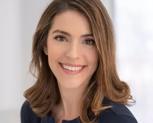 A young woman with brown, wavy hair posing for her headshot