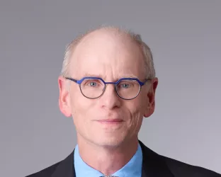 An older white man wearing a suit and tie with glasses