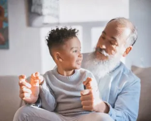 Man sitting on couch with small child on lap smiling at each other