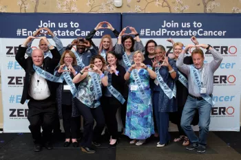 A group of people wearing blue ambassador sashes stand in front of a background that says Join Us To End Prostate Cancer