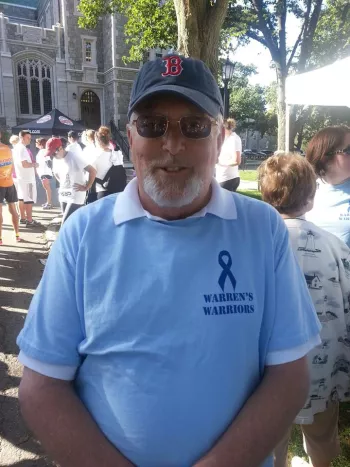 A man wearing a Boston cap and a blue Warren's Warriors shirt