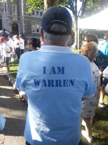 Man wearing a baseball cap at a crowded event where the shirt says "I Am Warren"