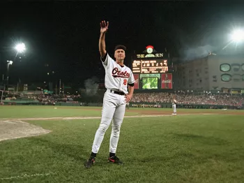 Cal Ripken Jr. standing on a baseball field holding his arm up