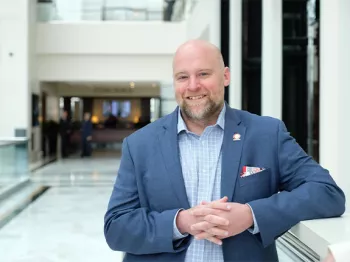 Jamie Bearse standing in a corridor leaning against a railing