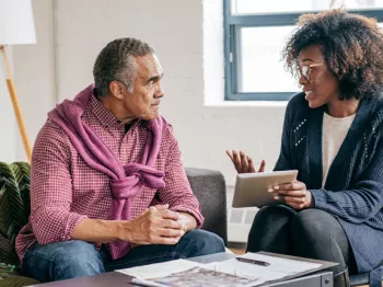 An older man speaking with a young adult who appears to be advising him