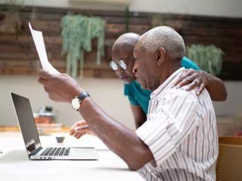 A black couple looking over paperwork and at a laptop