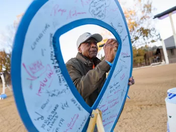 Black man signing a giant blue ribbon sign