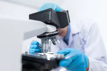 Scientist looking into microscope for prostate cancer research
