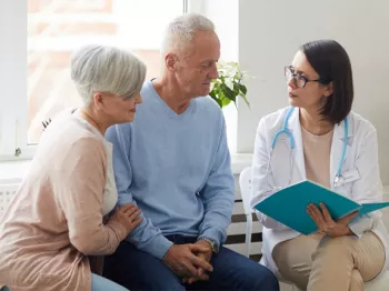 A senior couple speaking with a female doctor holding a folder