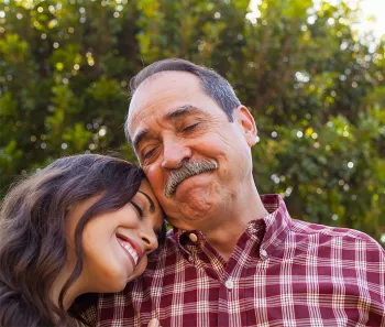 Older Hispanic man and his daughter leaning on his shoulder