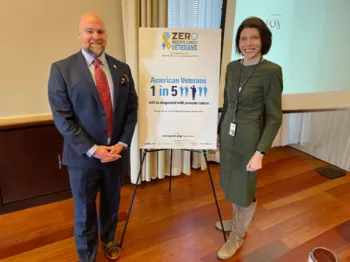 Jamie Bearse and a woman by a sign that says "1 in 5 Veterans will be diagnosed with prostate cancer"