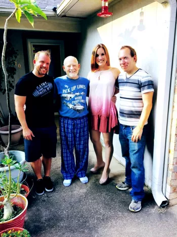 Brown Family posing for a photo outside of house by potted plants