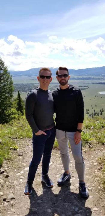 Chris Hartley  and his husband posing by roaming scenery