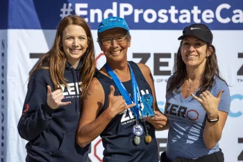 Randy Kam at a ZERO run/walk event sporting medals at the podium