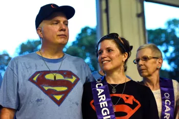 A tall man in a Superman t-shirt hugging a woman next to him