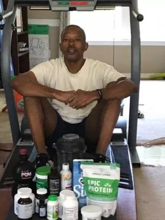 African American man posing in front of a pile of food supplements on a treadmill